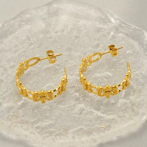 Vintage C-shaped hollow pattern gold titanium steel earrings on a glass tray