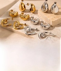 Macro detail of gold and silver teardrop and C-shape earrings on stone base