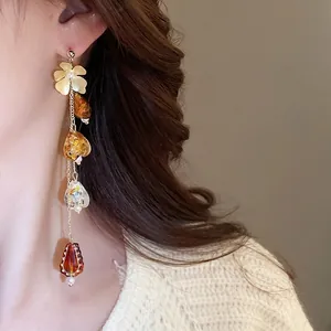 Boucles d'oreilles fleurs dorées avec pampilles en résine ambre et éclats de feuilles d'or