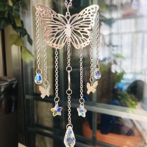 Detail of silver butterfly suncatcher with crystal teardrops and stars hanging by a window