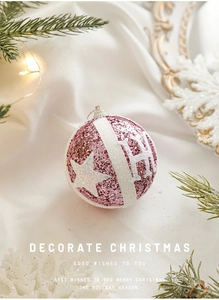 Detail of pink Christmas ornament ball with sequins and white stripes on snow background
