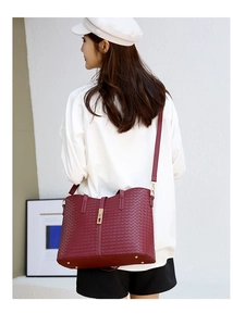 Détail d'un sac cabas bordeaux avec texture tressée, fermoir doré et bandoulière élégante