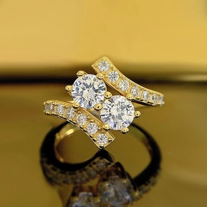 Vista macro de anillo dorado con dos diamantes redondos y banda cruzada de pavé