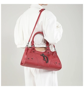 Detail of red leather tote bag with vintage metal cross chain and rivet hardware