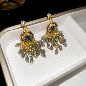 Detailed close-up of vintage gold tassel earrings with blue stones and grey faceted beads