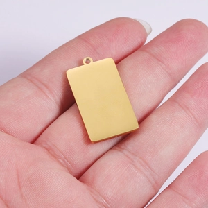 Golden rectangular stainless steel pendant with mirror finish held in hand for scale