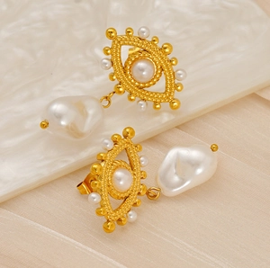 Macro detail of 18K gold eye-shaped earrings with baroque pearls and vintage texture
