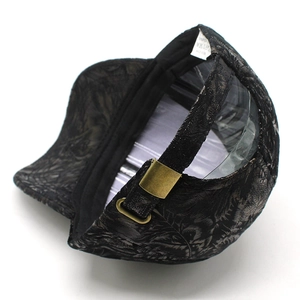 Détail du tissu jacquard à motif de feuilles et boucle de réglage en bronze sur la casquette