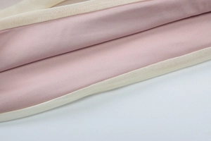Detail view of pink silky fabric and fine beige mesh stitching for women's dress