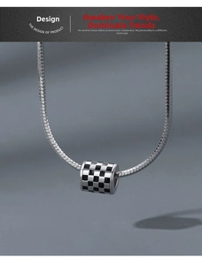 Detail of checkered cylinder pendant on a sleek flat snake chain necklace