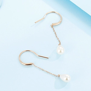 Elegant rose gold drop earrings with white teardrop pearls on a soft blue background