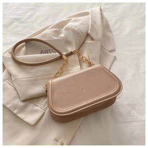 Detail of light beige saddle bag featuring gold chain strap and smooth faux leather finish