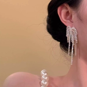 Elegant silver long tassel earrings with fireworks sparkle design worn by a model