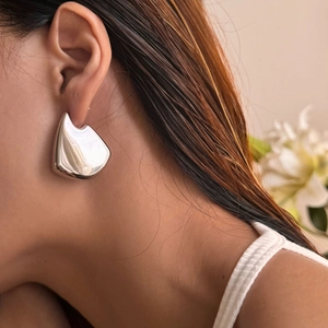 Close-up detail of silver vintage fan-shaped earrings with a polished mirror finish