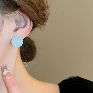 Détail macro d'une boucle d'oreille ronde en pierre oeil de chat bleu clair