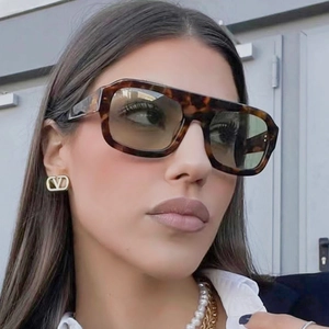 Close-up of tortoise square sunglasses with a gold V logo earring accessory