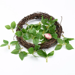 Macro shot of artificial rose branch with green leaves on hand-woven brown vine wreath