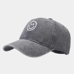 Detail of dark grey washed denim baseball cap with white embroidered smiley face