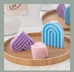 Creative pastel heart and rainbow scented candles arranged on a wooden tray for home decor