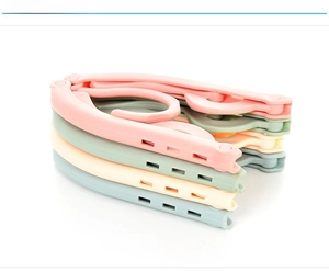 Detail of four foldable portable plastic travel hangers in pink green yellow and blue