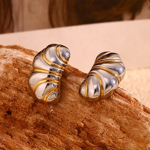 Vue macro de boucles d'oreilles croissant bicolores or et argent sur fond de bois