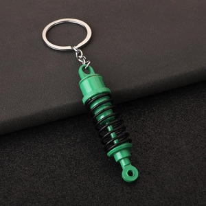 Detail of green and black metal car shock absorber keychain with realistic spring design