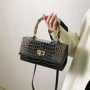 Detailed view of black croc-embossed leather texture with bamboo handle and gold lock