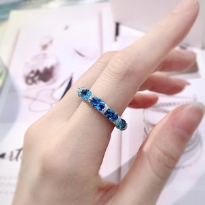 Close-up of silver ring with five oval-cut blue gems and sparkling pave diamonds