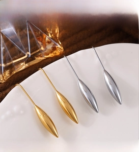 Close-up of gold and silver teardrop earrings on a white plate with PVD coating text