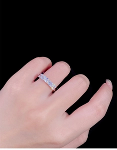 Macro shot of silver ring set with rectangular cut zircons on a hand against black