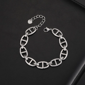 Macro shot of silver stainless steel pig nose anchor chain bracelet on black leather texture