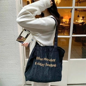 Detail of navy blue denim tote bag with gold embroidery and spacious interior texture
