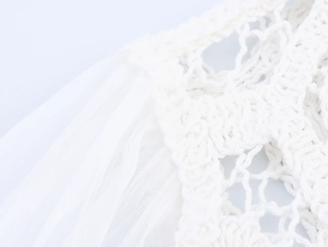 Macro detail of white crochet lace patterns and pleated chiffon texture on long sleeve top
