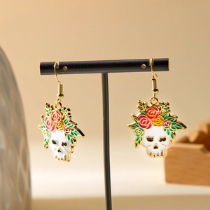 Close-up of Halloween skull earrings with colorful oil-painted roses and green leaves
