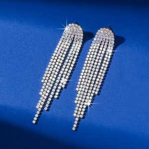 Detail of long silver tassel earrings with sparkling rhinestones on blue background