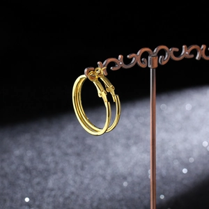 Macro detail of glossy gold hoop earrings with secure plug-in closure on black background