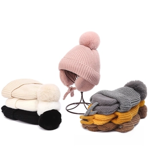 Close-up of thick knit winter hats with faux fur pom-poms and warm fleece lining details