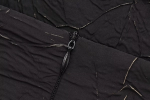 Close-up of black pleated fabric with gold threads and high-quality invisible zipper