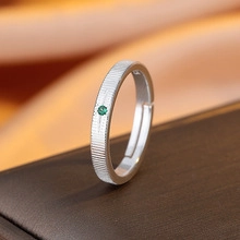Macro detail of silver adjustable ring with brushed texture and round green gemstone inlay
