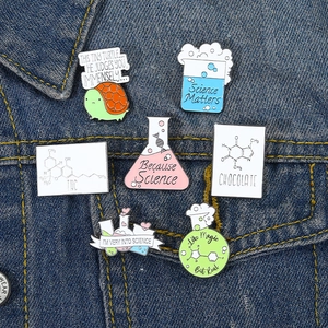 Scientific enamel pins set with laboratory flasks and molecules on denim jacket