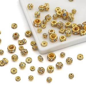Golden rhinestone spacer beads for DIY jewelry making displayed on a white ceramic plate