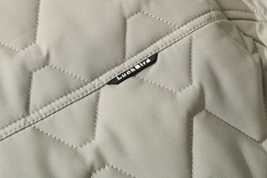Detailed close-up of light khaki quilted jacket with star stitching and logo label