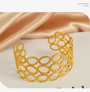 Close-up of golden hollow oval layered cuff bracelet on premium champagne satin background