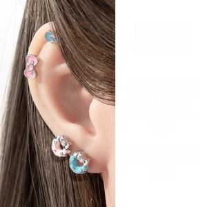 Detail of pink and blue enamel bow and donut cartilage earrings with crystal accents