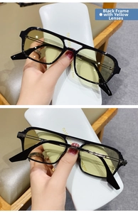 Detail view of modern black double-bridge sunglasses with yellow transparent lenses