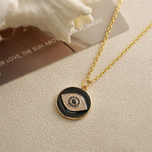 Close-up of golden evil eye necklace with blue crystals on a textured fabric background