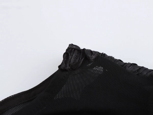 Close-up of black mesh fabric detail with twisted woven decorative edging on a gown