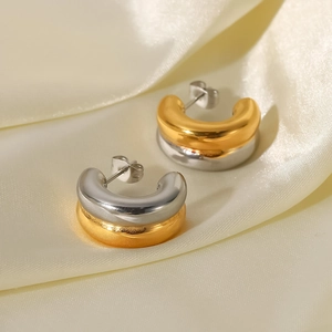 Details von zweifarbigen 18K Gold und Silber U-Ohrringen auf cremefarbenem Satinstoff