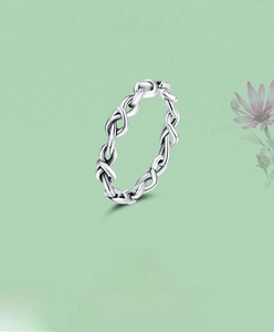 Detailed close-up of S925 sterling silver infinity knot ring on floral background