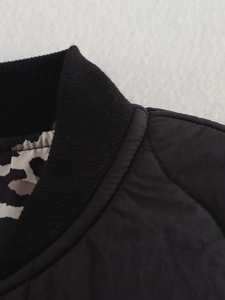 Detail of black quilted jacket featuring ribbed collar and leopard print lining